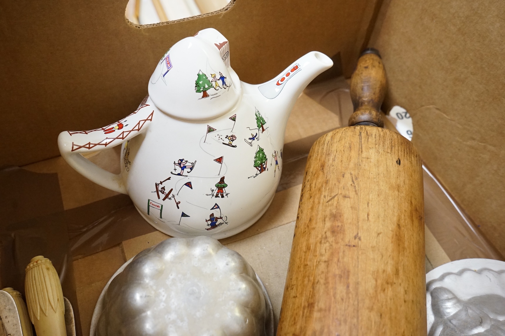 A collection of Kitchenalia, including a Wade novelty teapot, a large wooden rolling pin, jelly moulds, etc.